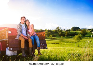 Senior Couple Sitting In Back Of Red Pickup Truck