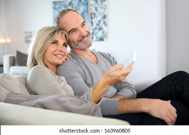 Senior Couple Sitting In Couch And Watching Tv