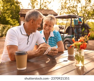 Senior Couple Sitting Having Coffee After Round Of Golf Looking At Score Card Together - Powered by Shutterstock