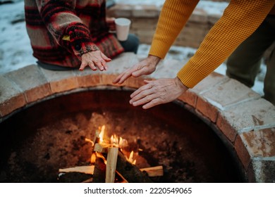 Senior couple sitting and heating together at outdoor fireplace in winter evening. - Powered by Shutterstock