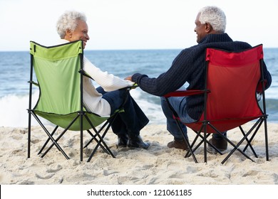 Senior Couple Sitting On Beach In Deckchairs