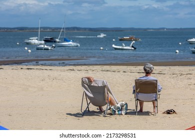 Senior Couple Sitting On The Beach Looking At The Sea