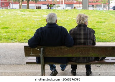 Senior Couple Sitting On Bench From Behind. Anonymous Retired Husband And Wife In The Park