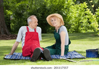 Senior couple sitting on a blanket in the garden