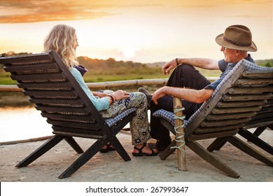 Senior couple sitting on chairs with their backs at the camera on sunset time in Chitwan national park, Nepal - Powered by Shutterstock