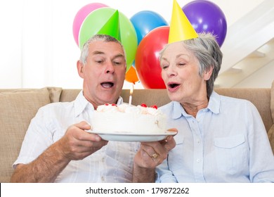 Senior Ehepaar sitzend auf Couch bei einem Geburtstag zu Hause im Wohnzimmer