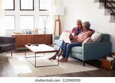 Senior Couple Sitting On Sofa At Home Using Laptop To Shop Online - Powered by Shutterstock