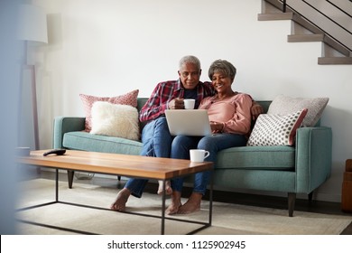 Senior Couple Sitting On Sofa At Home Using Laptop To Shop Online - Powered by Shutterstock