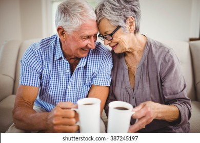 Senior Couple Sitting On Sofa And Having Coffee In Living Room