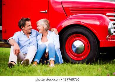 Senior couple sitting at the red vintage car - Powered by Shutterstock