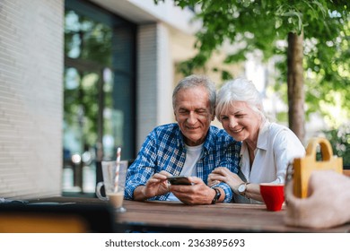 Senior couple sitting at a table in a cafe and using mobile phone
 - Powered by Shutterstock