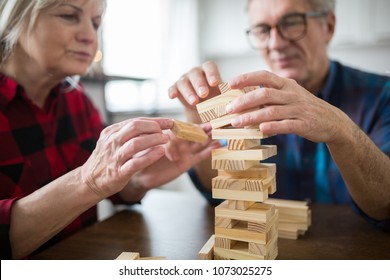 Senior Couple Sitting At Table Playing Jenga