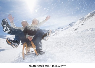 Senior Couple Sledding In Mountains