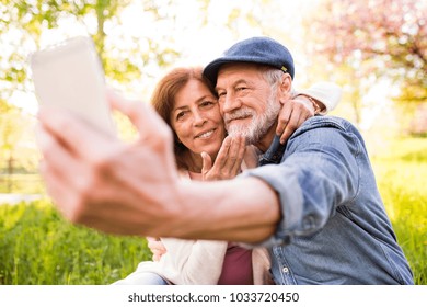 Senior Couple With Smartphone Outside In Spring Nature.