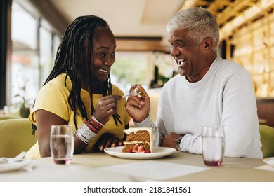 Senior couple smiling at each other while sharing a delicious cake in a cafe. Happy senior couple having a good time in a restaurant. Cheerful mature couple enjoying their retirement together. - Powered by Shutterstock