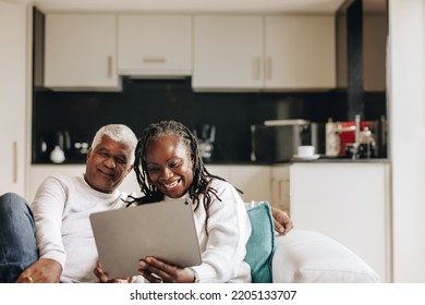 Senior couple smiling happily while having a video call on a digital tablet. Carefree senior couple communicating with their loved ones online. Mature couple enjoying their retirement at home. - Powered by Shutterstock