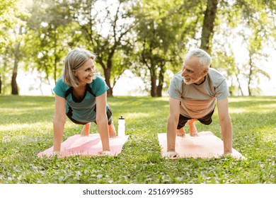 Senior couple, smiling, mature man and woman doing plank exercise together outdoors in park on yoga mat. Fitness, sport concept - Powered by Shutterstock