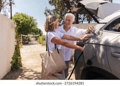 Senior couple smiling while plugging electric vehicle into charging station, embracing sustainable travel and enjoying their retirement lifestyle outdoors