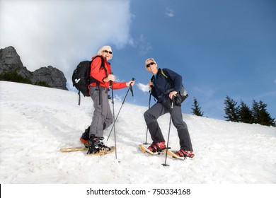 Senior Couple Snowshoeing In Mountains