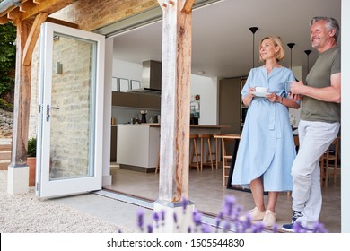 Senior Couple Standing And Looking Out Of Kitchen Door Drinking Coffee - Powered by Shutterstock