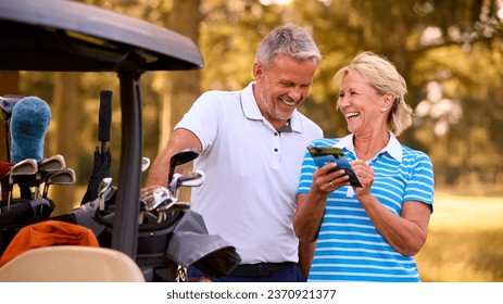 Senior Couple Standing Next To Buggy On Golf Course Marking Score Card Together - Powered by Shutterstock