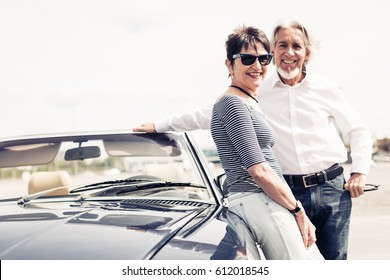 Senior Couple Standing Next To Convertible Classic Car