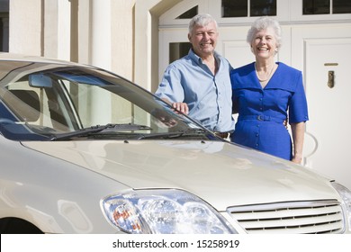 Senior Couple Standing Next To New Car Outside House