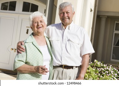 Senior Couple Standing Outside Front Door Of Home