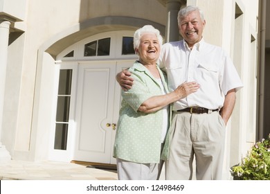 Senior Couple Standing Outside Front Door Of House