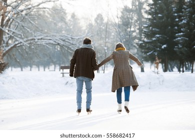 Senior Couple In Sunny Winter Nature Ice Skating, Rear View.