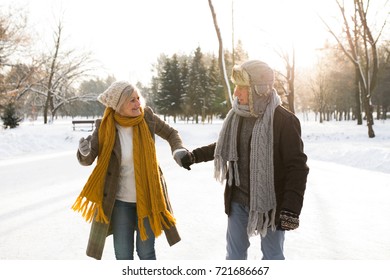 Senior Couple In Sunny Winter Nature On A Walk.