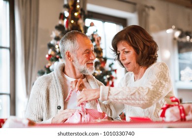 Senior couple in sweaters wrapping Christmas gifts together. - Powered by Shutterstock