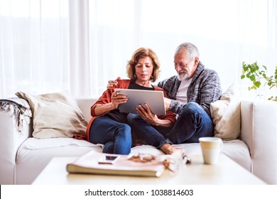 Senior Couple With Tablet Relaxing At Home.