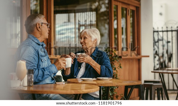 カフェでコーヒーを飲みながら話す老夫婦 喫茶店に座ってコーヒーを飲みながら会話をする老人と女性 の写真素材 今すぐ編集