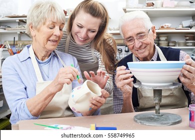 Senior Couple With Teacher In Pottery Class