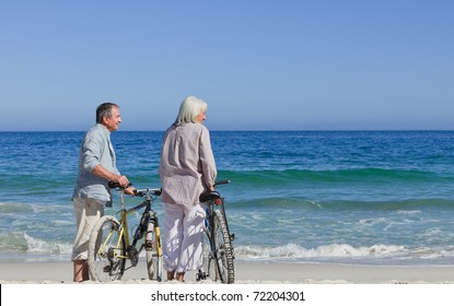 Senior Couple With Their Bikes On The Beach