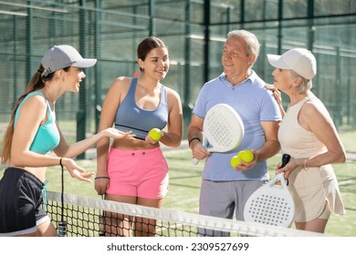 Senior couple and their daughters discussing padel game in court - Powered by Shutterstock