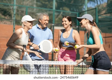 Senior couple and their daughters discussing padel game in court - Powered by Shutterstock