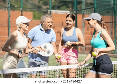 Senior couple and their daughters discussing padel game in court - Powered by Shutterstock