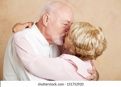 Senior Couple In Their Eighties Exchanging A Passionate, Romantic Kiss.  