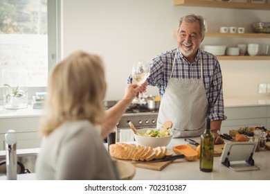 Senior Couple Toasting Wine Glasses At Home