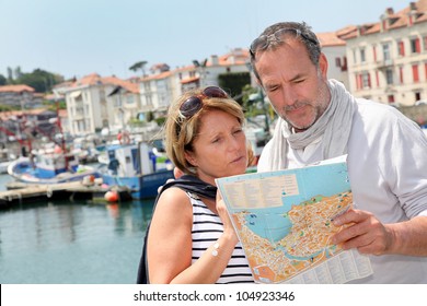 Senior Couple In Touristic Area Looking At Map