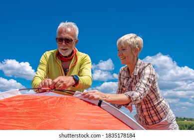 Senior couple tourists having fun together while putting up a tent in nature - Powered by Shutterstock