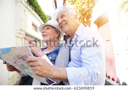 Senior couple of tourists looking at city map 
