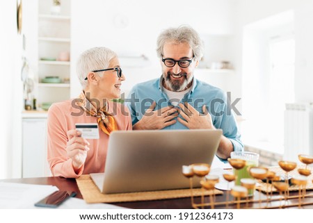 Senior couple using credit card for shopping online using laptop