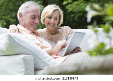 Senior couple using digital tablet on outdoor sofa - Powered by Shutterstock