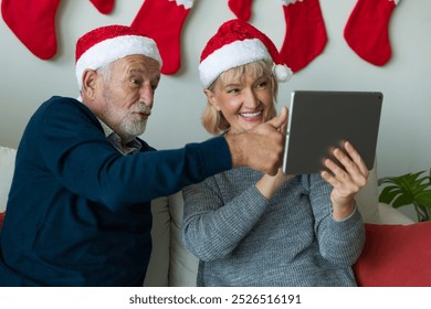 Senior couple using digital tablet on Christmas day. Elderly couple with digital tablet at home. Merry Christmas and Happy Holidays - Powered by Shutterstock