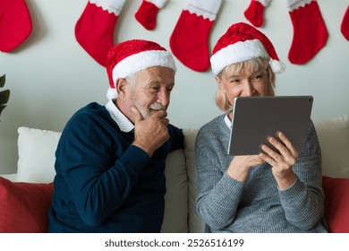 Senior couple using digital tablet on Christmas day. Elderly couple with digital tablet at home. Merry Christmas and Happy Holidays - Powered by Shutterstock