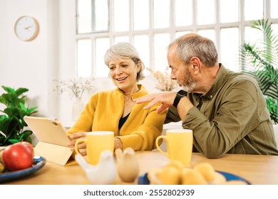 Senior couple using digital tablet at home having breakfast - Powered by Shutterstock