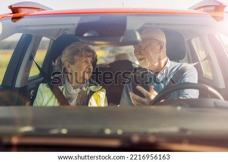 Senior couple using gps on their mobile phone during a road trip
